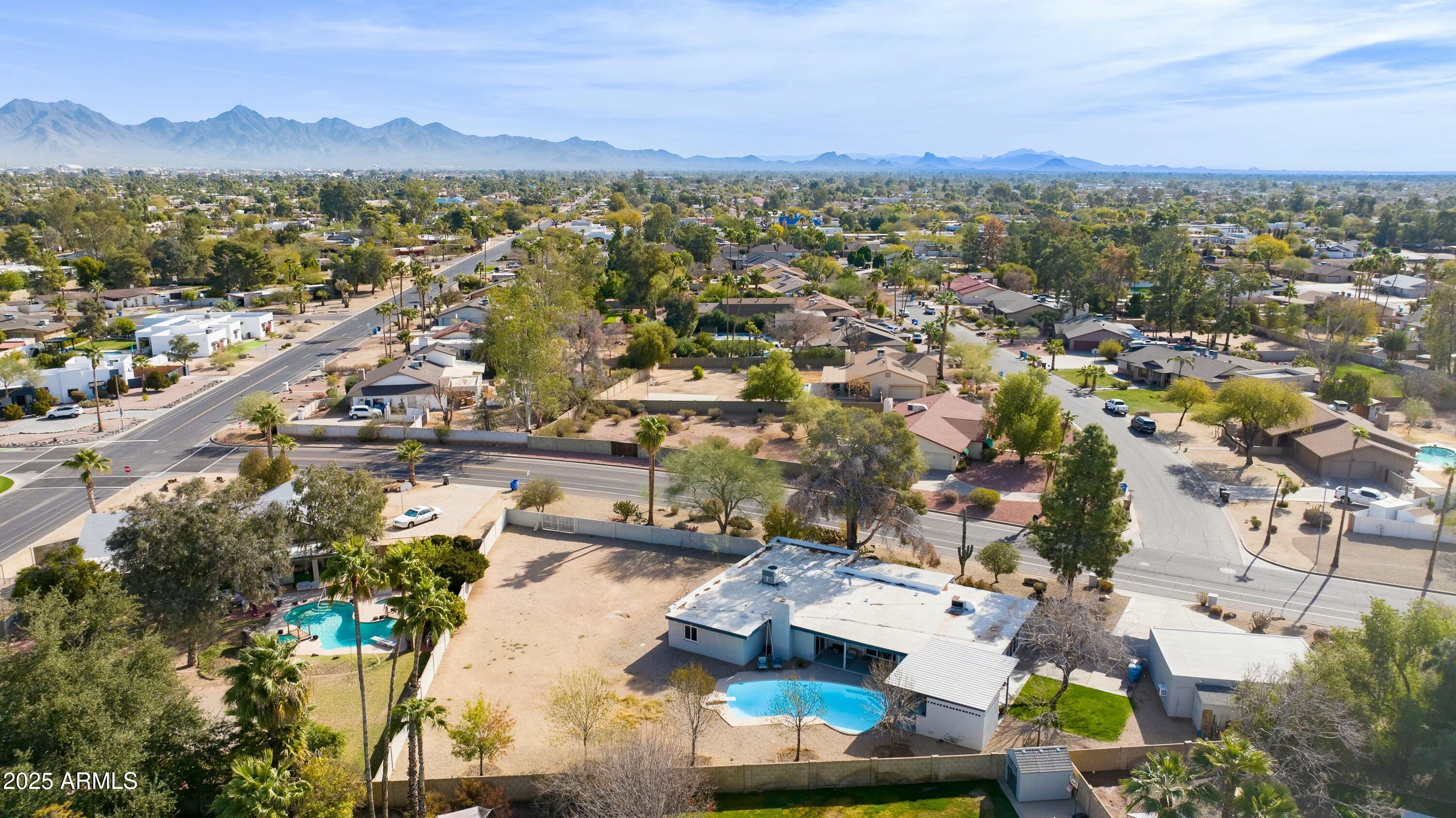 Aerial view of a Scottsdale home with a swimming pool, spacious yard, and distant mountain range.