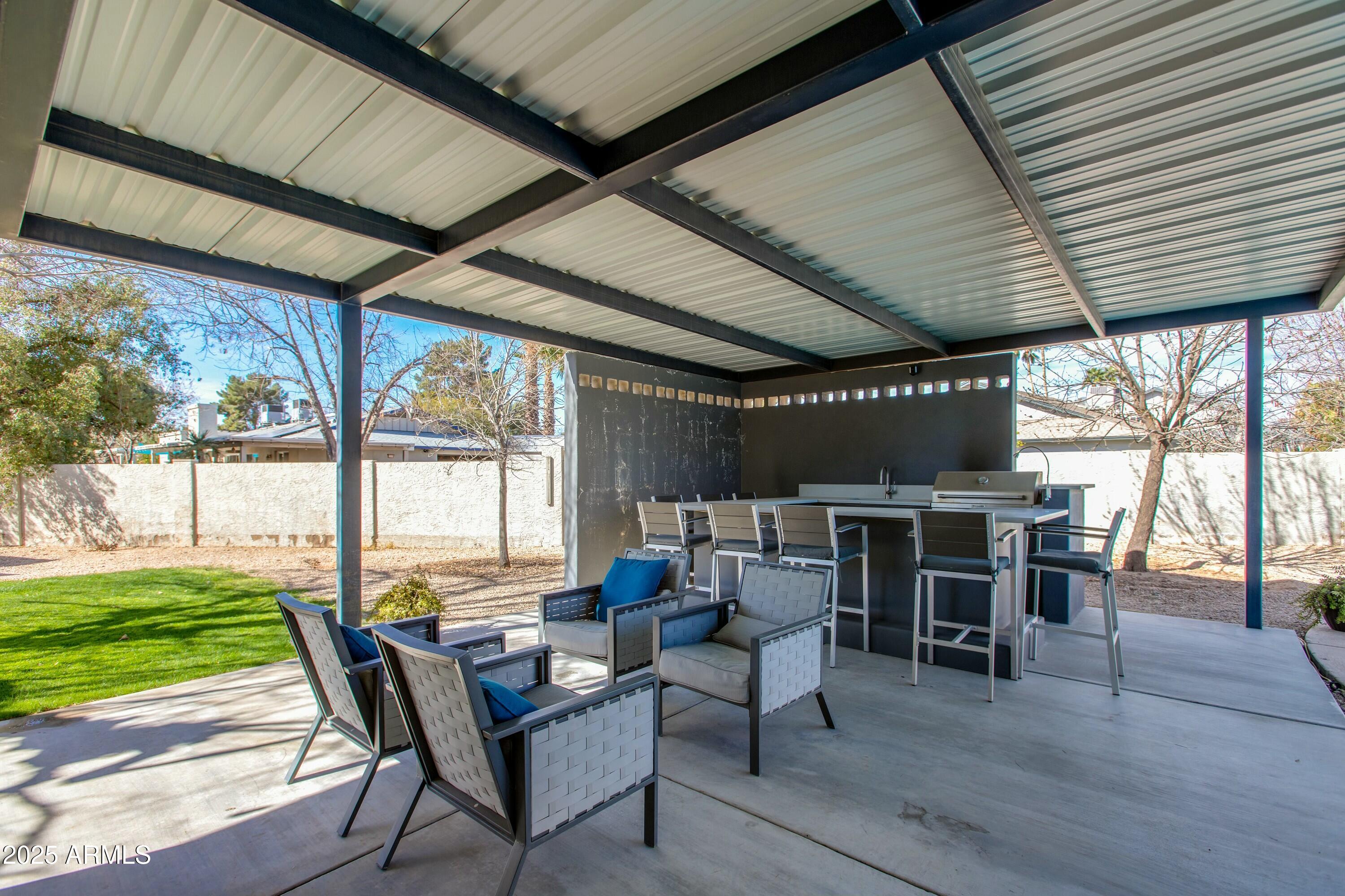 Covered patio with lounge seating, an outdoor dining counter, and built-in grill