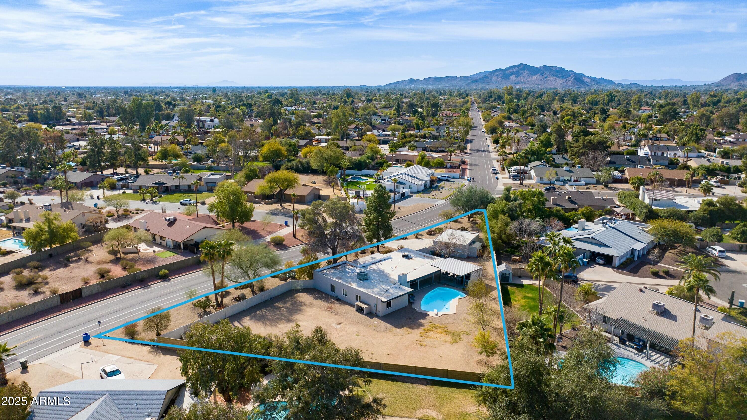 Aerial view of a home and large outlined lot with a pool and mountain backdrop.