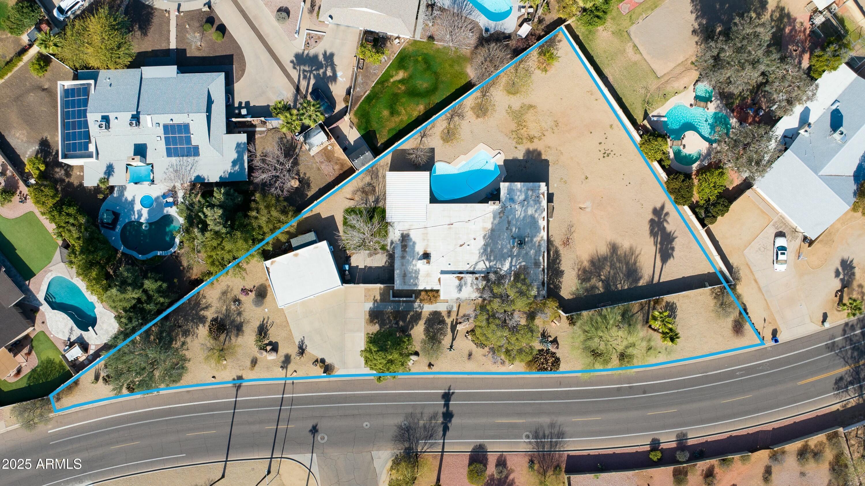 Aerial view of the property outlined in blue, showing its house, pool, and expansive desert-landscaped lot.