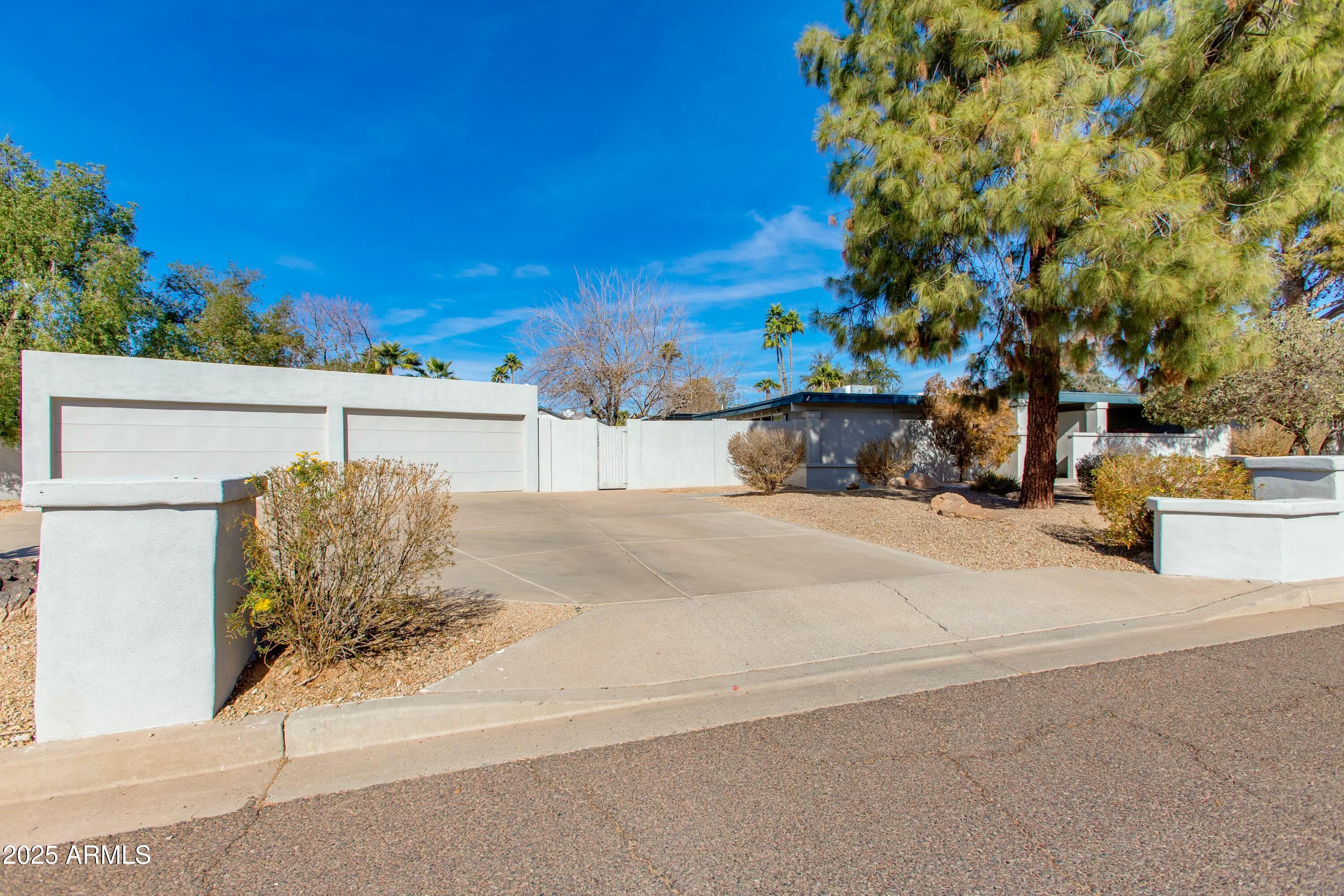 Modern single-story home with two garage doors, a wide driveway, and desert landscaping.