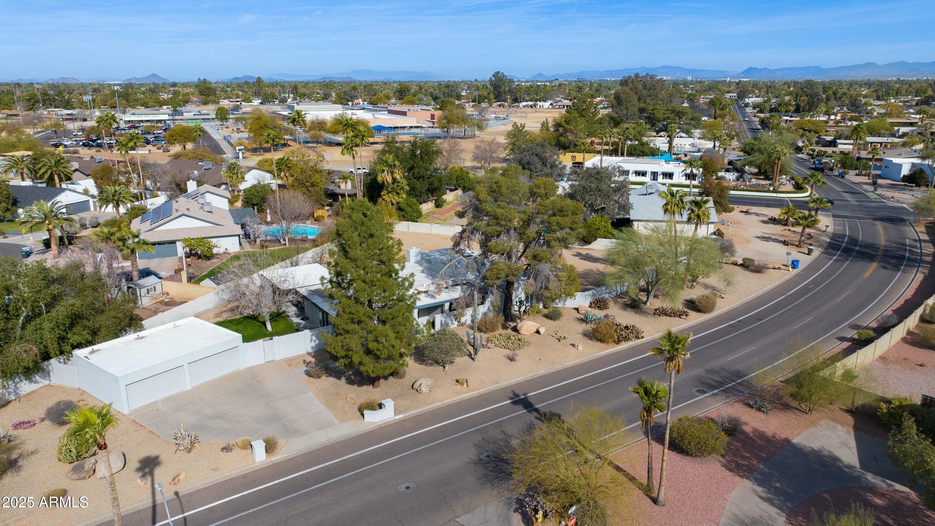 Aerial view of a Scottsdale home with a large white garage, desert landscaping, and distant mountains.