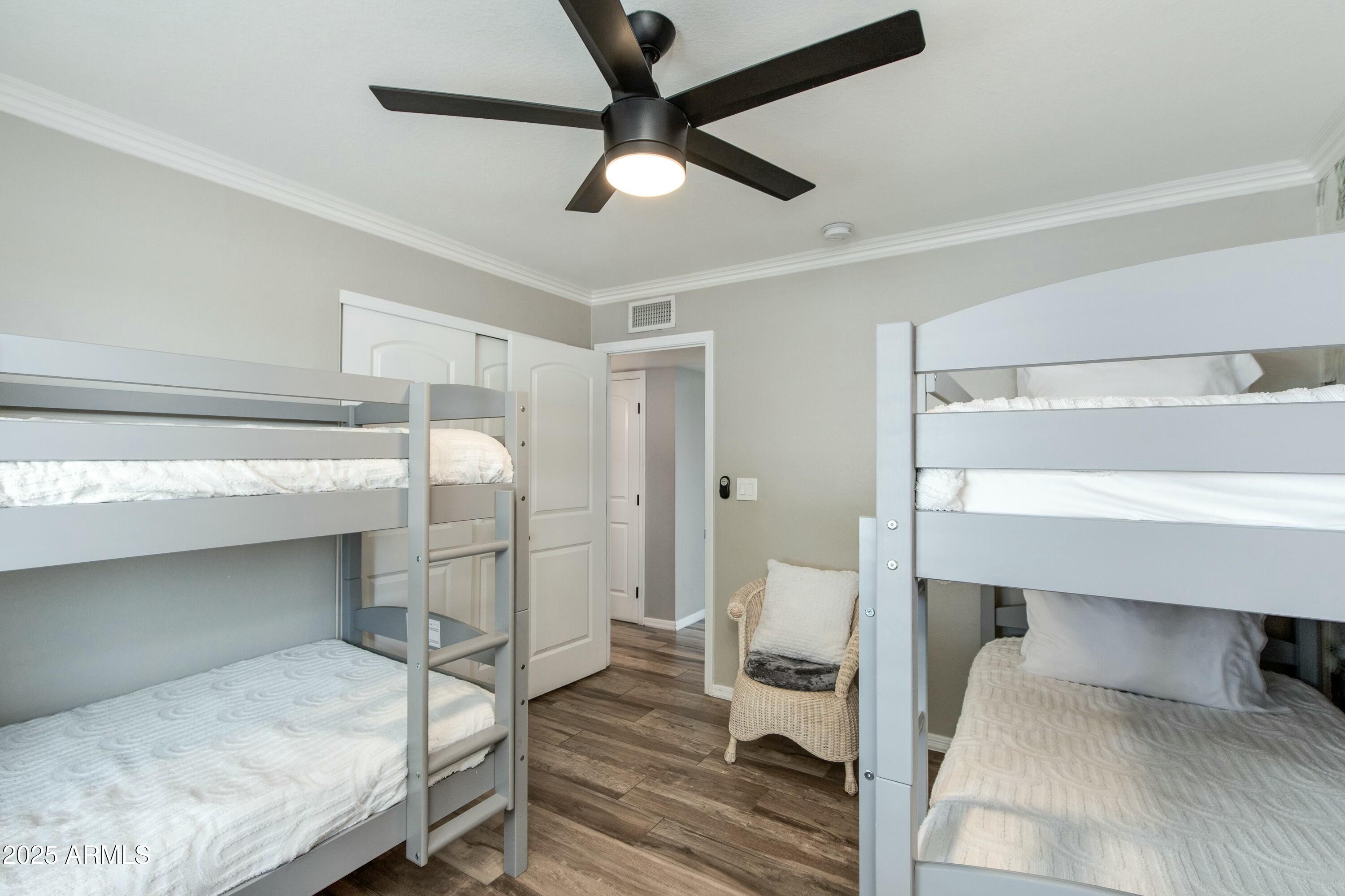 Bedroom with two gray bunk beds, white bedding, a ceiling fan, and a wicker chair.