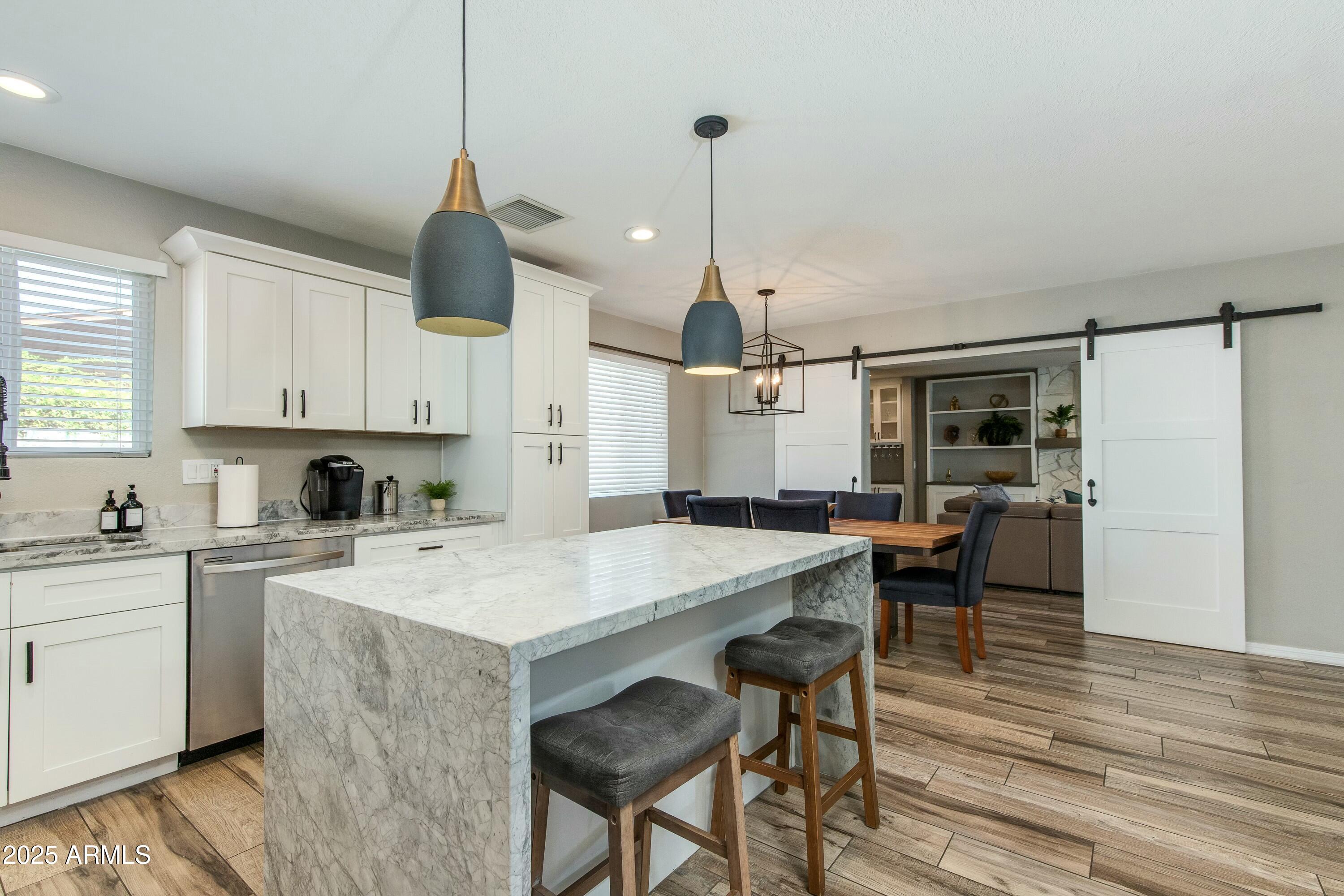 Kitchen with a large marble-look island, white cabinets, and sliding barn doors opening to the dining area.