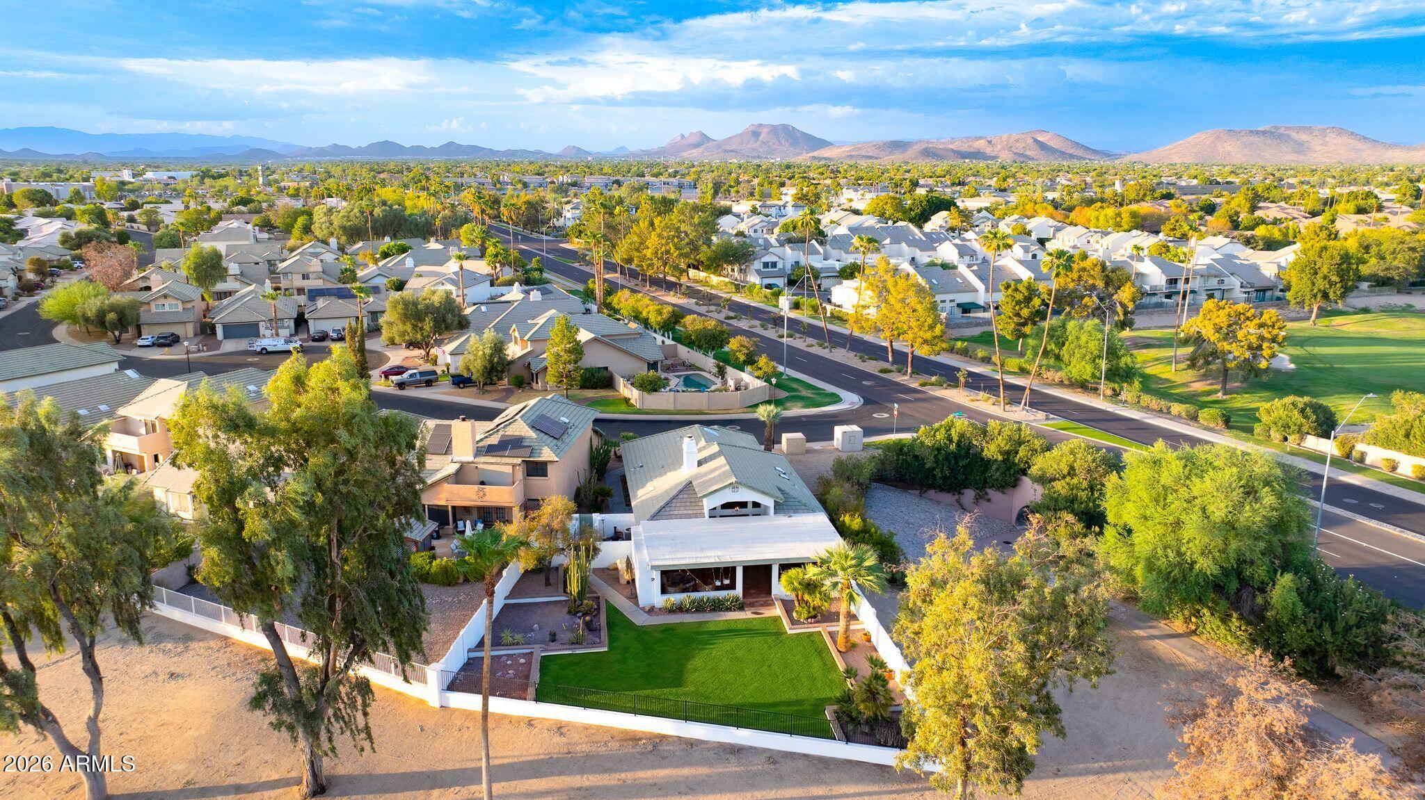 Aerial view of a Glendale home with a green lawn, pool, and mountain views.