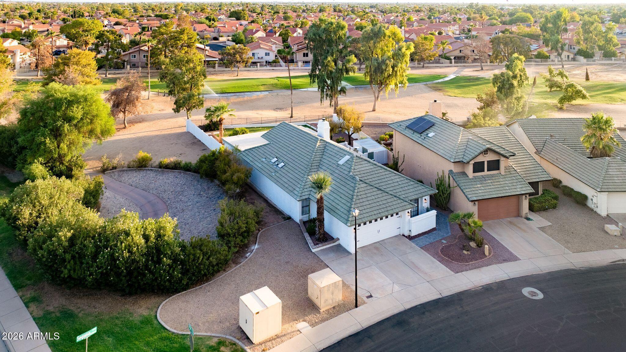Aerial view of a tiled-roof home beside a green park and neighborhood.