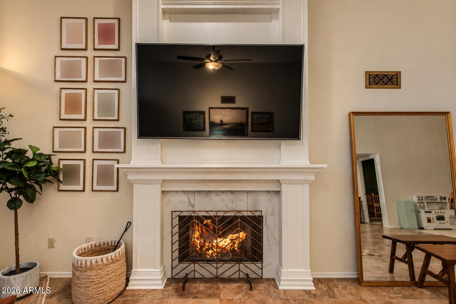 Living room fireplace with a marble surround, geometric screen, and large television above the mantel.