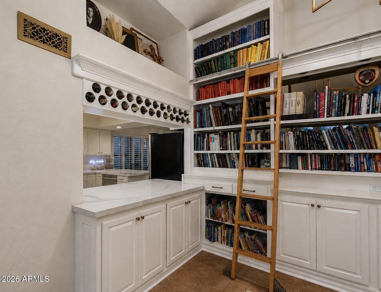 Home library with floor-to-ceiling bookshelves, a rolling ladder, and white built-in cabinetry.