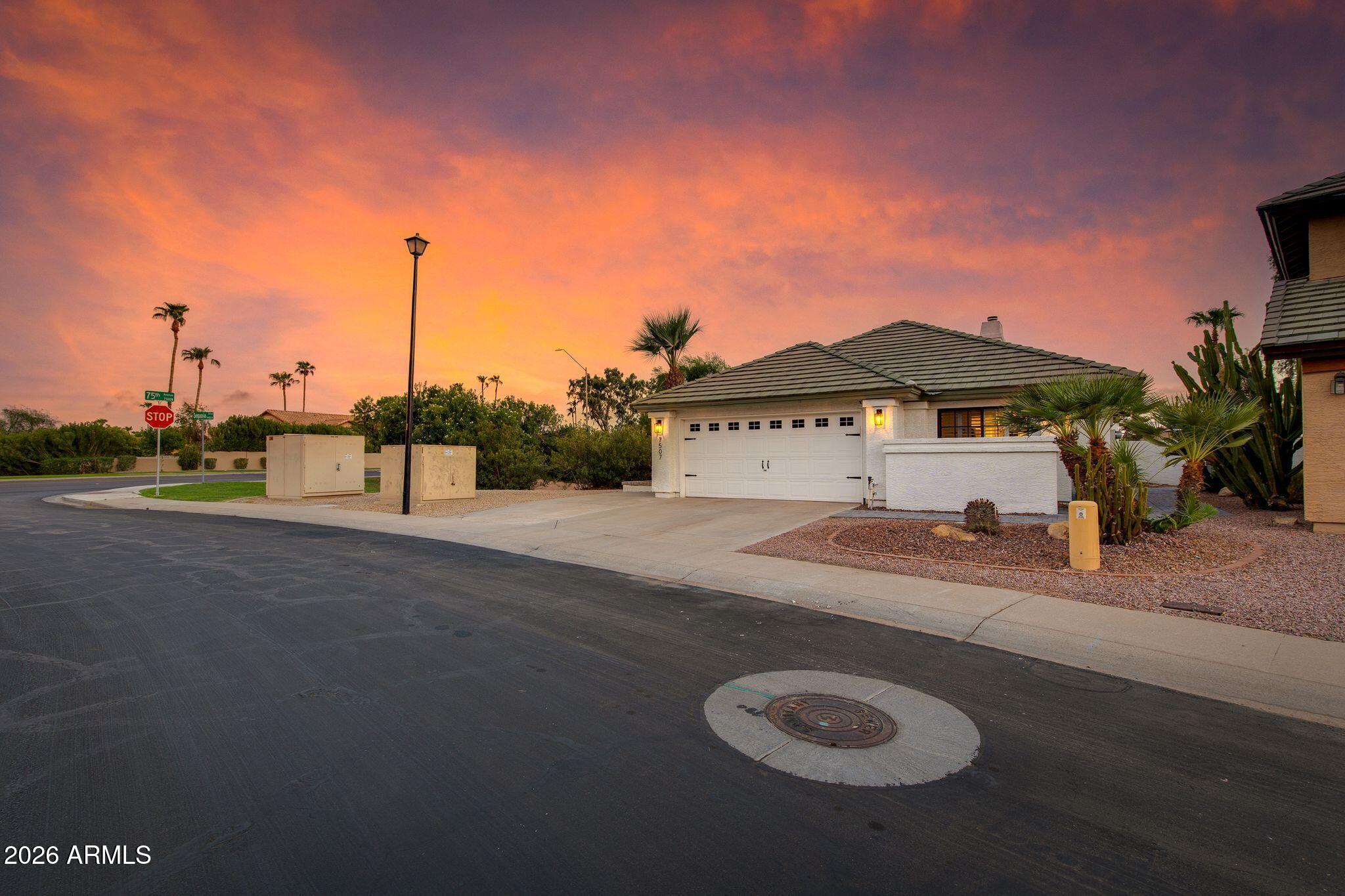 Single-story home with a tiled roof, two-car garage, and desert landscaping at sunset.