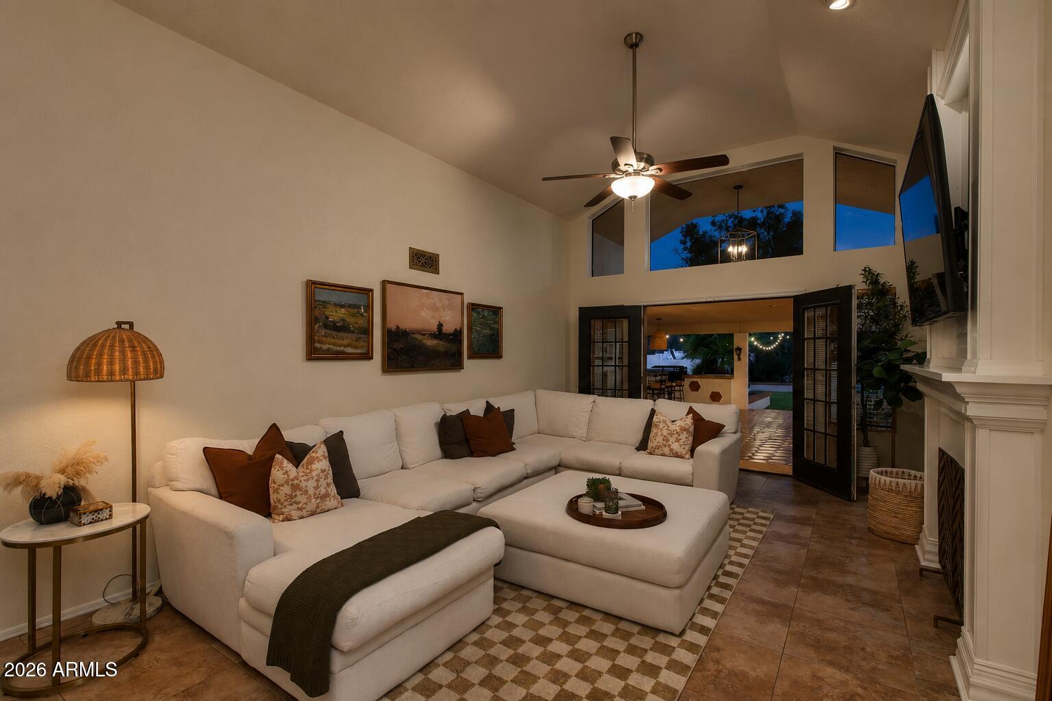 Living room with a white sectional, high windows, and open doors to a patio at dusk.