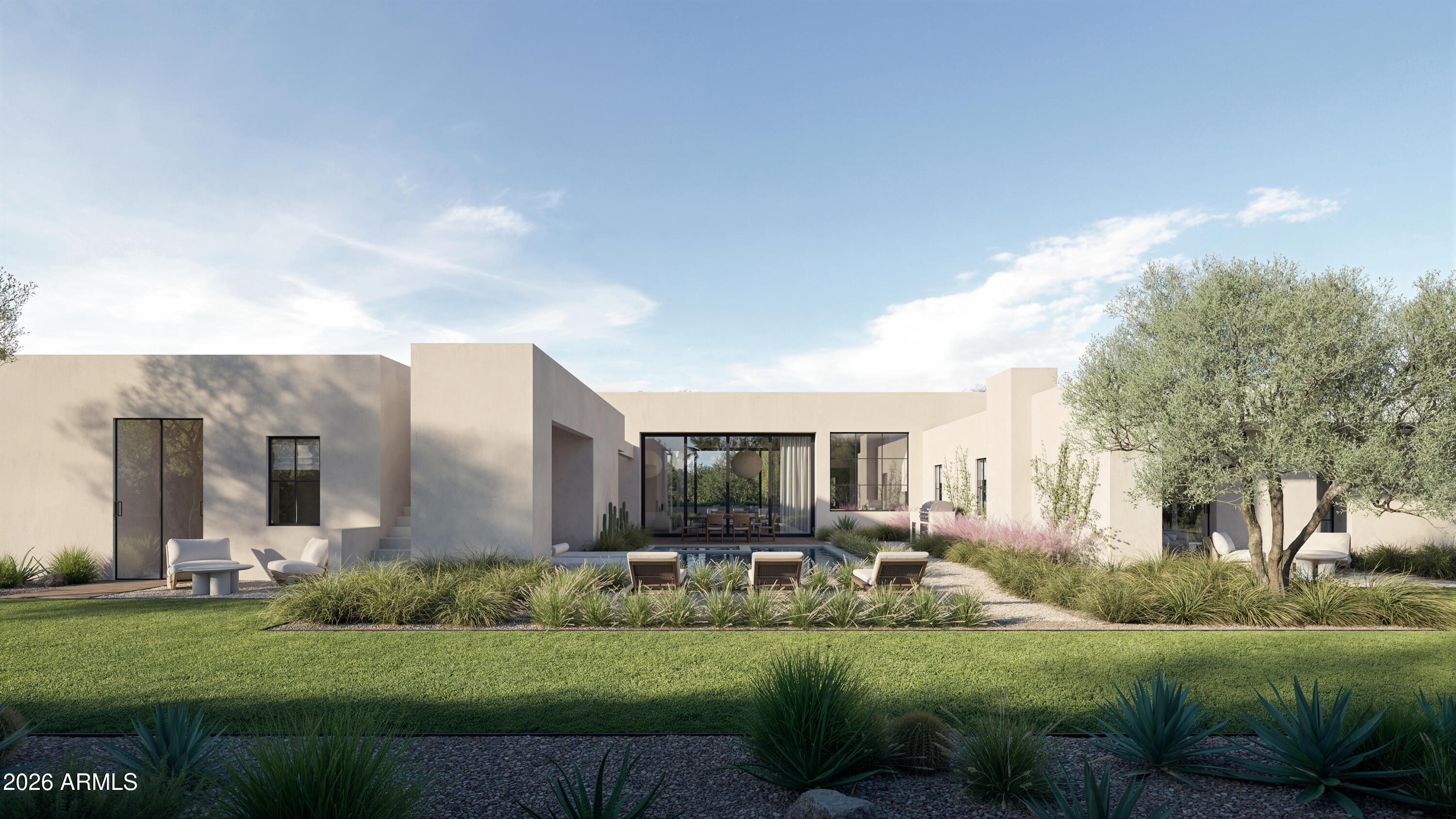 Modern home’s rear courtyard with a small pool, lounge chairs, and landscaped lawn.