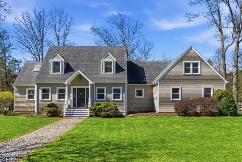 Tan-sided house with dormer windows, a stone walkway, and a broad front lawn.