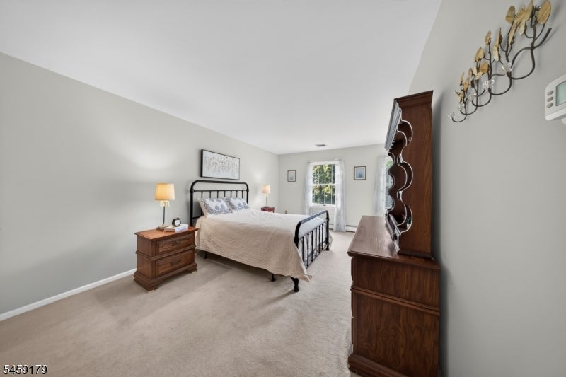 Furnished bedroom with a black metal bed, neutral bedding, and dark wood furniture.