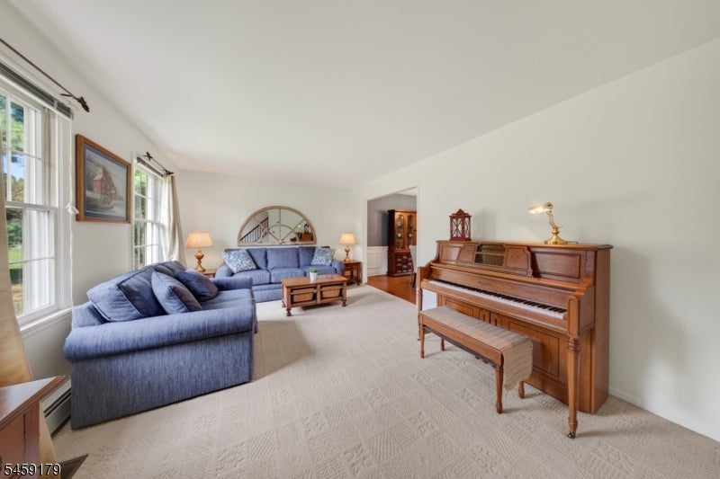 Living room with blue sofas and a wooden upright piano beside tall windows.