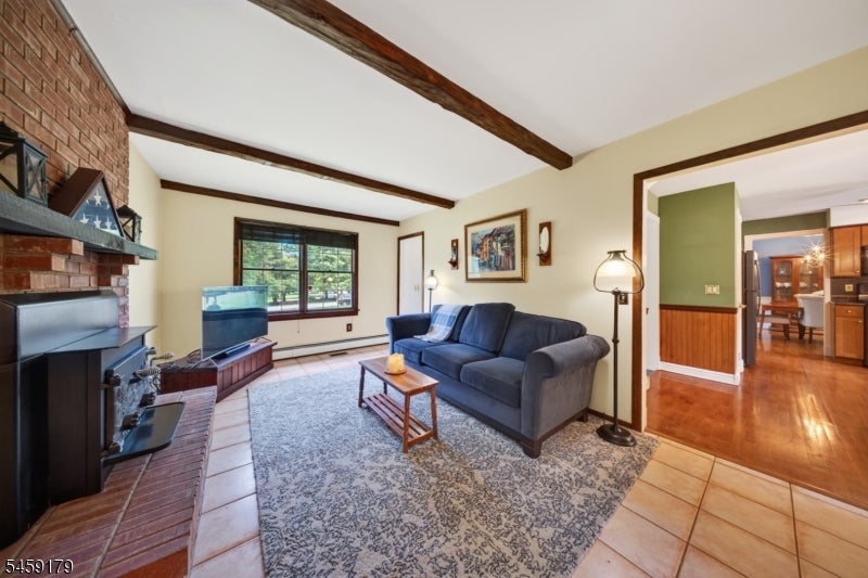 Living room with brick fireplace, exposed beams, blue sofa, and doorway to the kitchen.