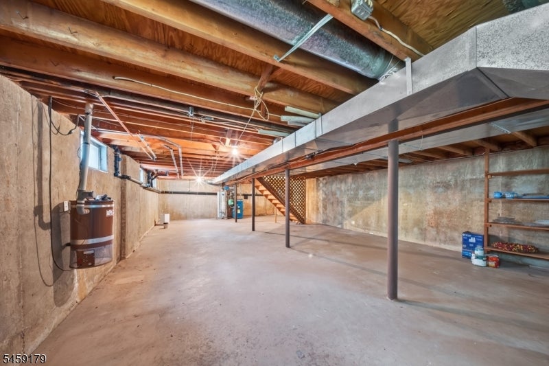 Unfinished basement with exposed ceiling joists, steel support beams, and a concrete floor.