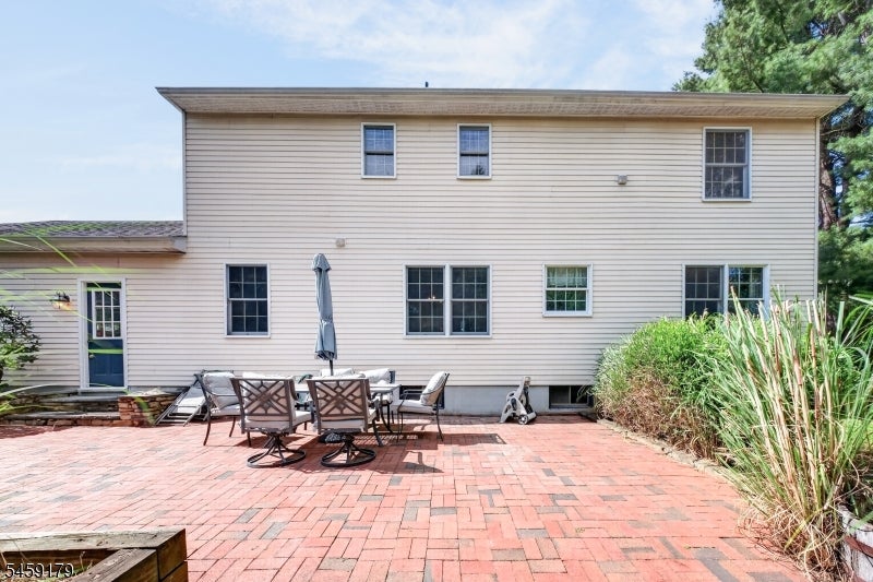 Two-story home's rear exterior with a brick patio and outdoor dining set.