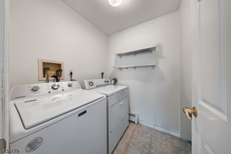 Laundry room with a Maytag washer and dryer, wall-mounted shelves, and tiled flooring.