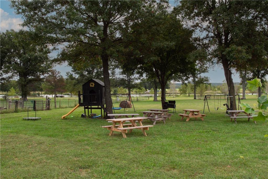 Shaded grassy yard with picnic tables, a play structure, and swings.
