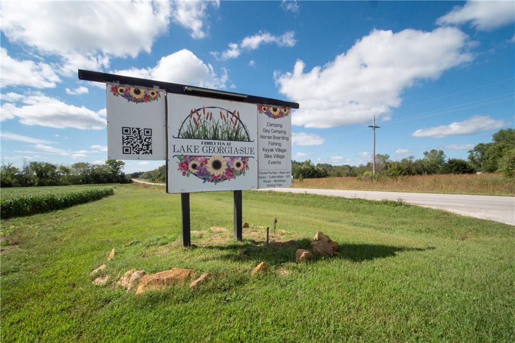 Lake Georgia-Sue roadside sign beside a rural road and grassy property.