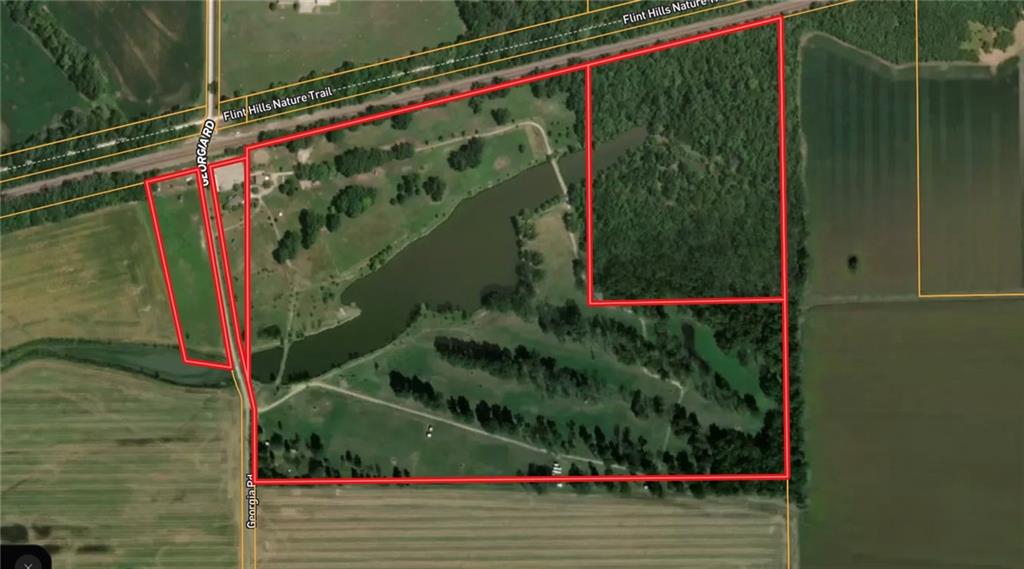 Aerial view of rural land with a pond and wooded area outlined in red.