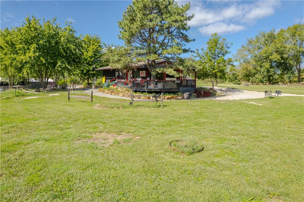 Dark house with a covered porch, mature trees, and a broad grassy lawn.