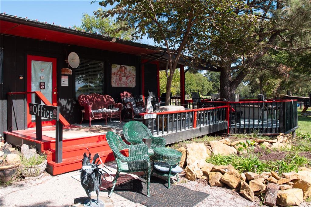 Office exterior with a red-trimmed raised deck, outdoor seating, and mature trees.