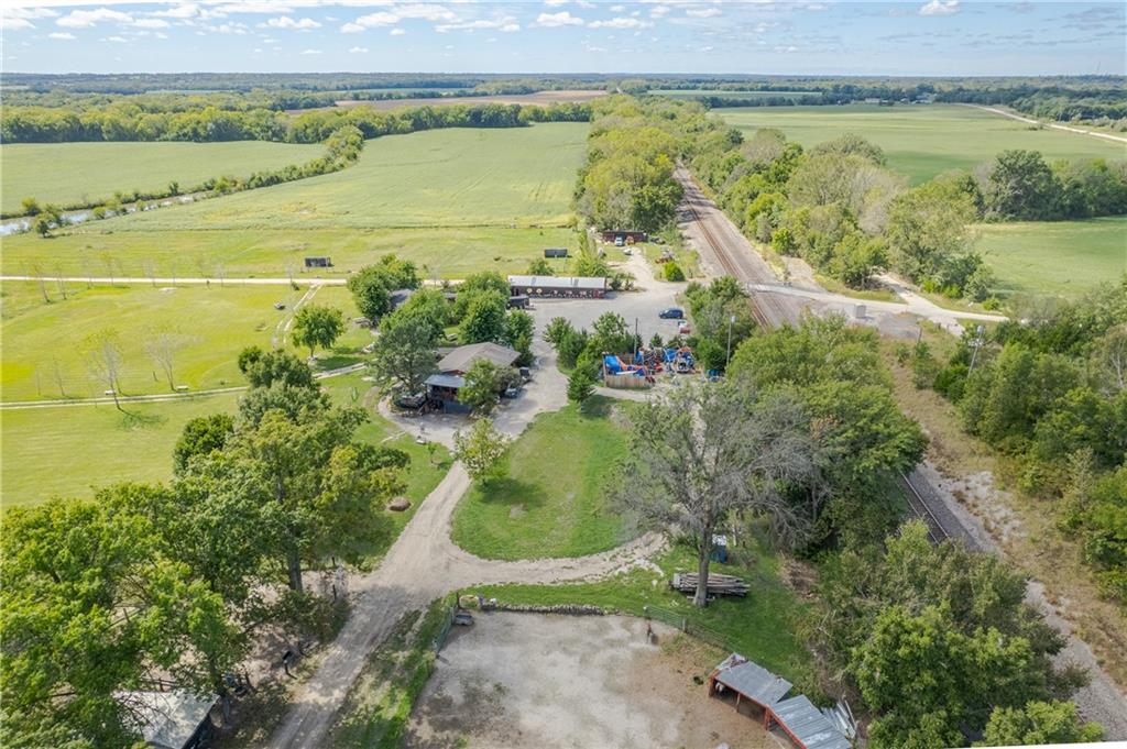 Aerial view of a rural property with buildings, a playground, surrounding fields, and a railroad track.