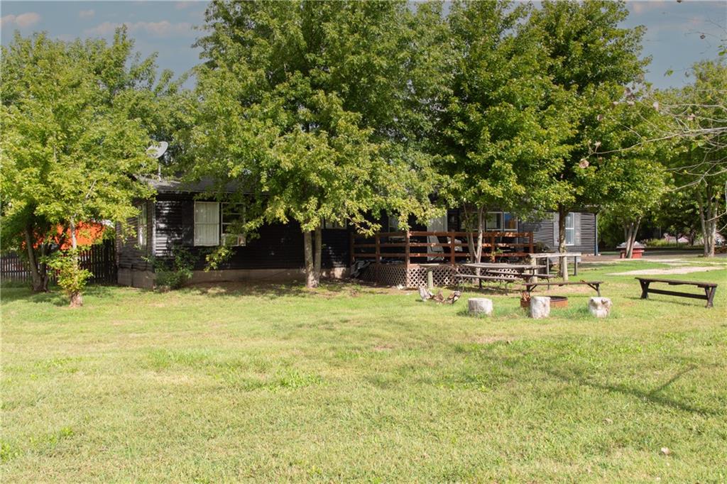 Tree-shaded home with a raised deck, fire-pit seating, and broad lawn.