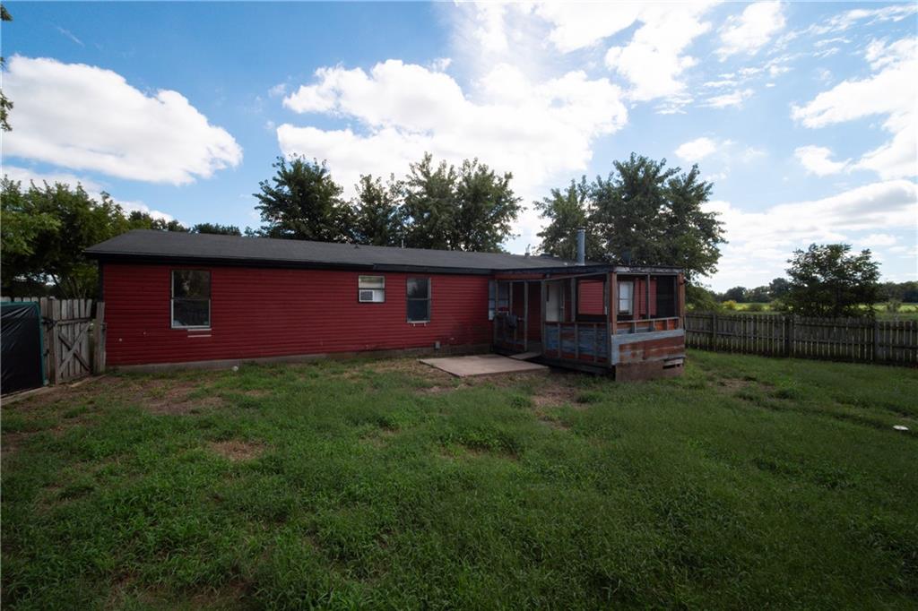 Red-sided home with a screened porch and small deck in a fenced grassy yard.