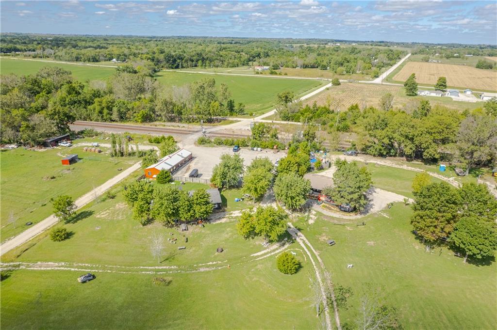 Rural property with open pasture, scattered trees, and several outbuildings.