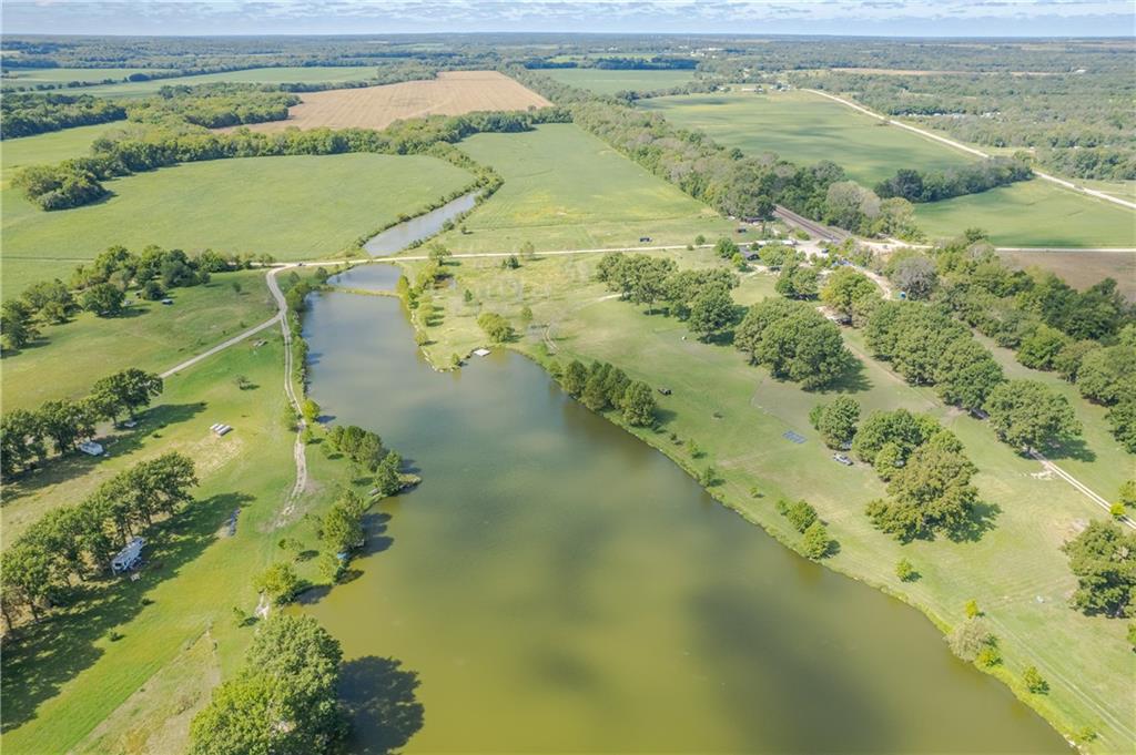 Aerial view of a large pond bordered by grassy fields and trees.