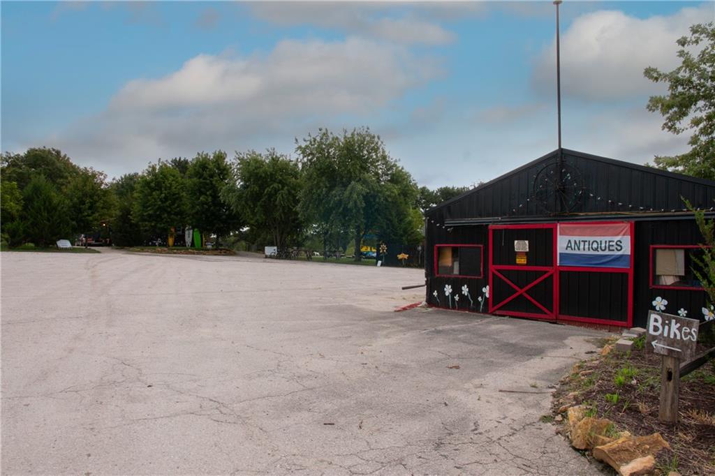 Small black antiques shop with red trim beside a broad paved parking area.