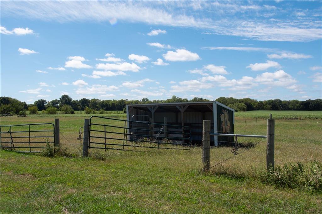 Fenced pasture with an open-sided livestock shelter and metal gates.