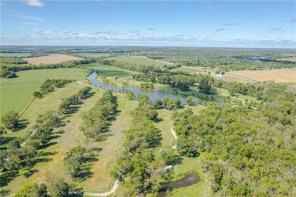 Rural acreage with a large pond, smaller pond, open fields, and tree-lined paths.
