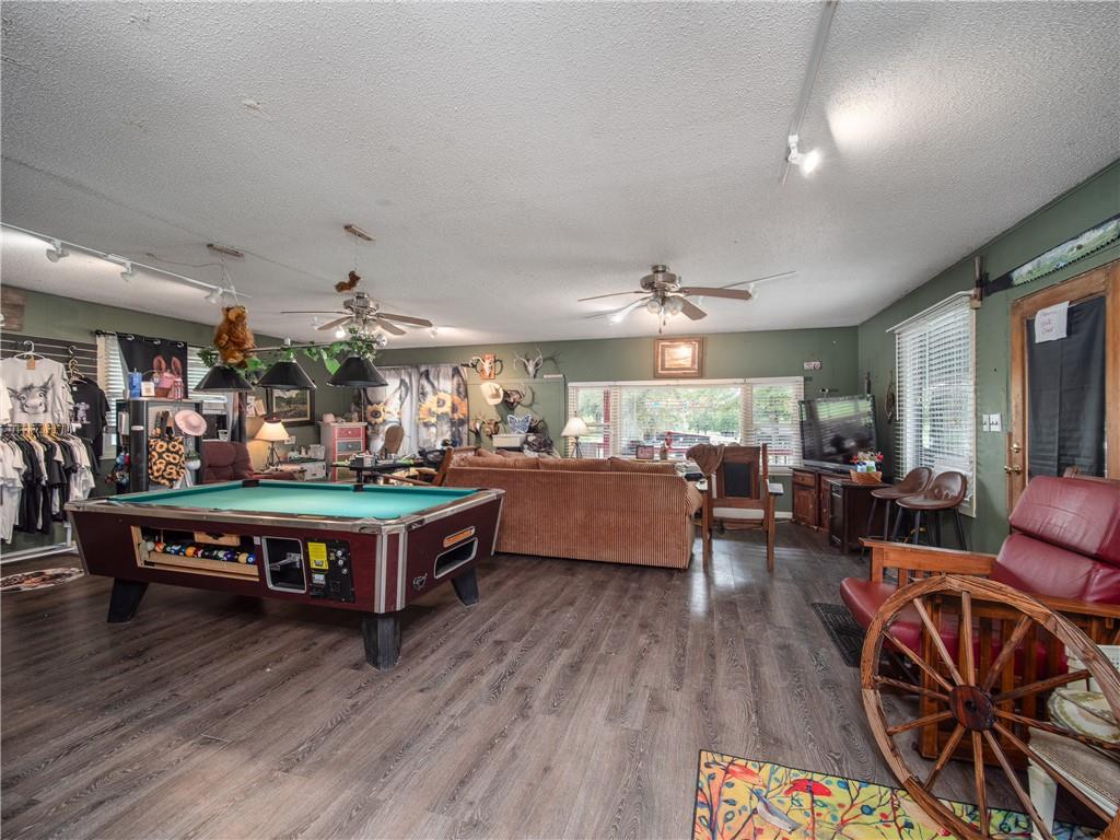 Recreation room with a green-felt pool table, lounge seating, and large windows.
