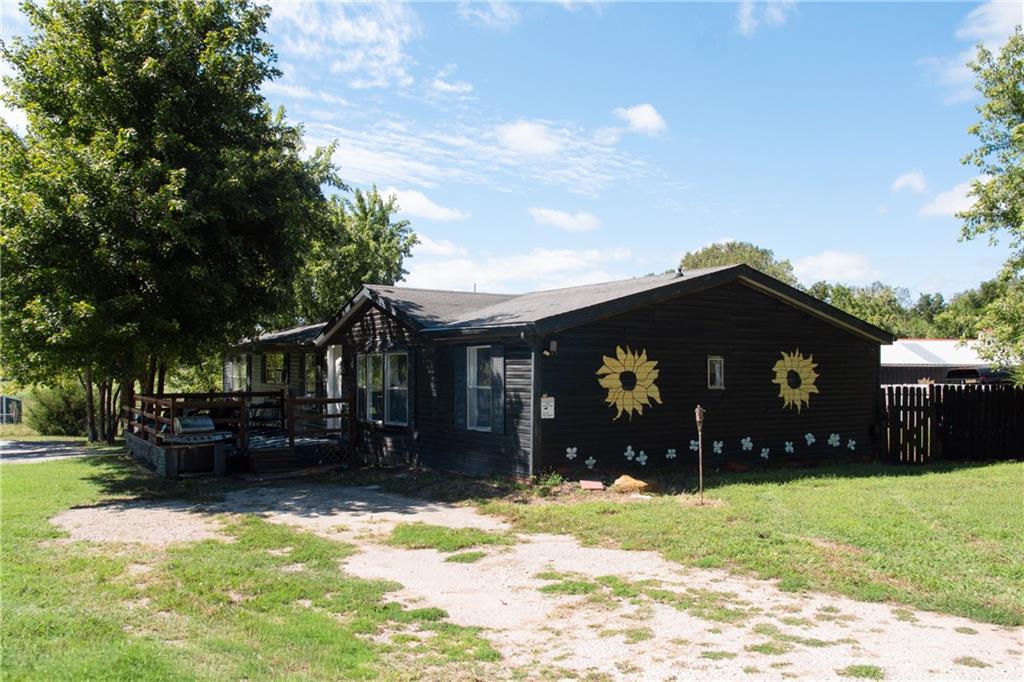 Black single-story house with a wooden porch and sunflower decorations on the side wall.