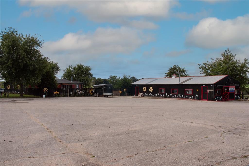 Black single-story building with red trim and flower murals beyond a broad paved parking lot.