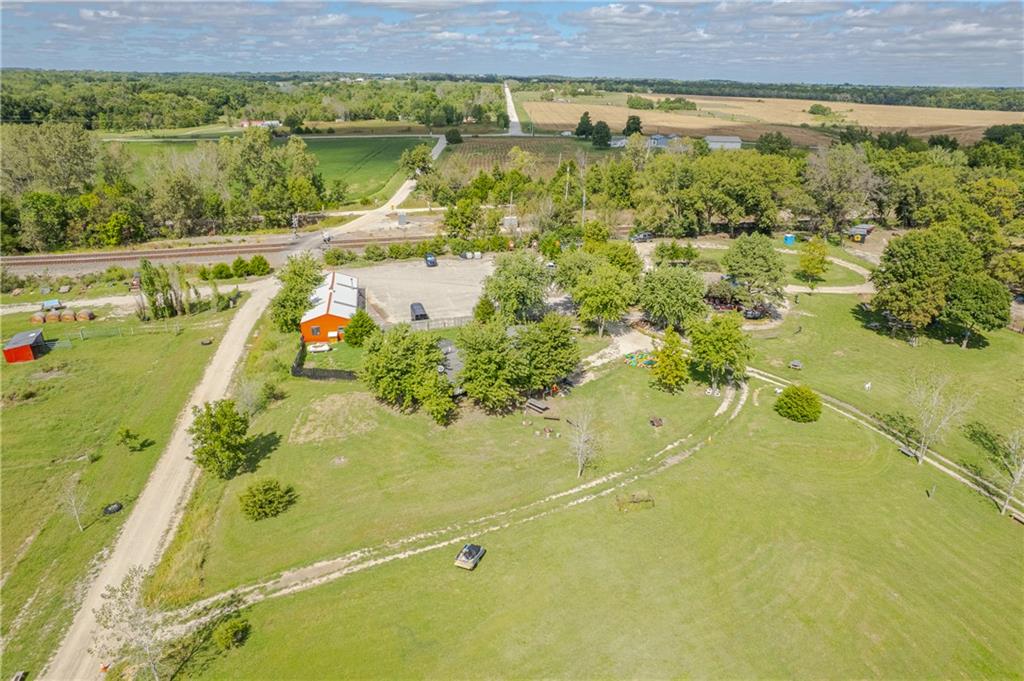Aerial view of a rural property with broad lawns, mature trees, and an orange outbuilding.