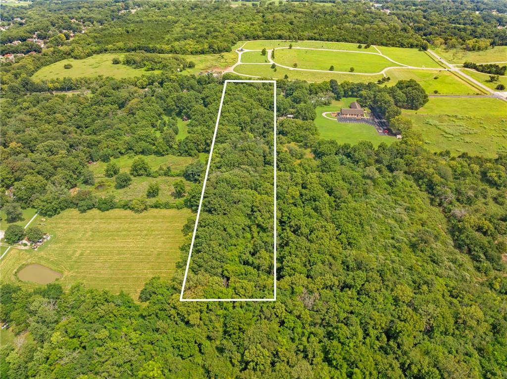 Aerial view of a wooded property parcel outlined in white beside open fields.