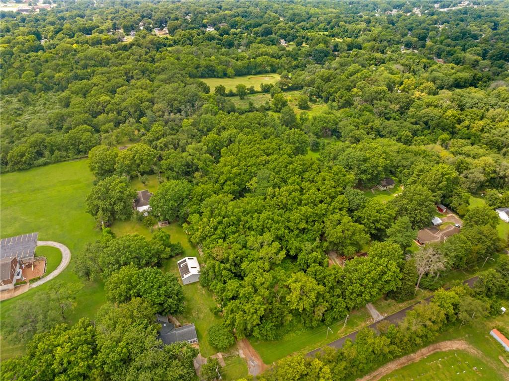 Aerial view of a heavily wooded property with scattered homes and open lawns.