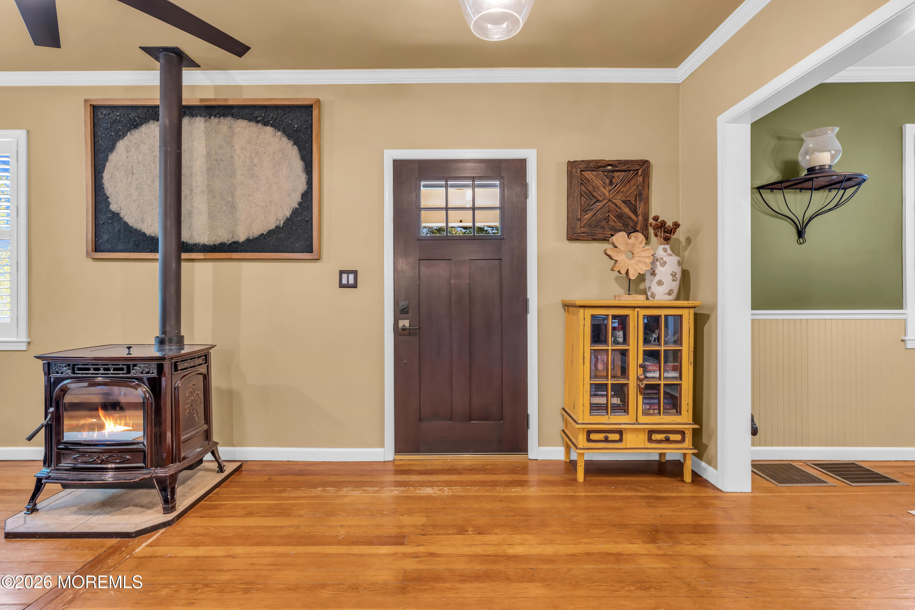 Entryway with a lit wood stove, dark front door, and yellow glass-front cabinet.