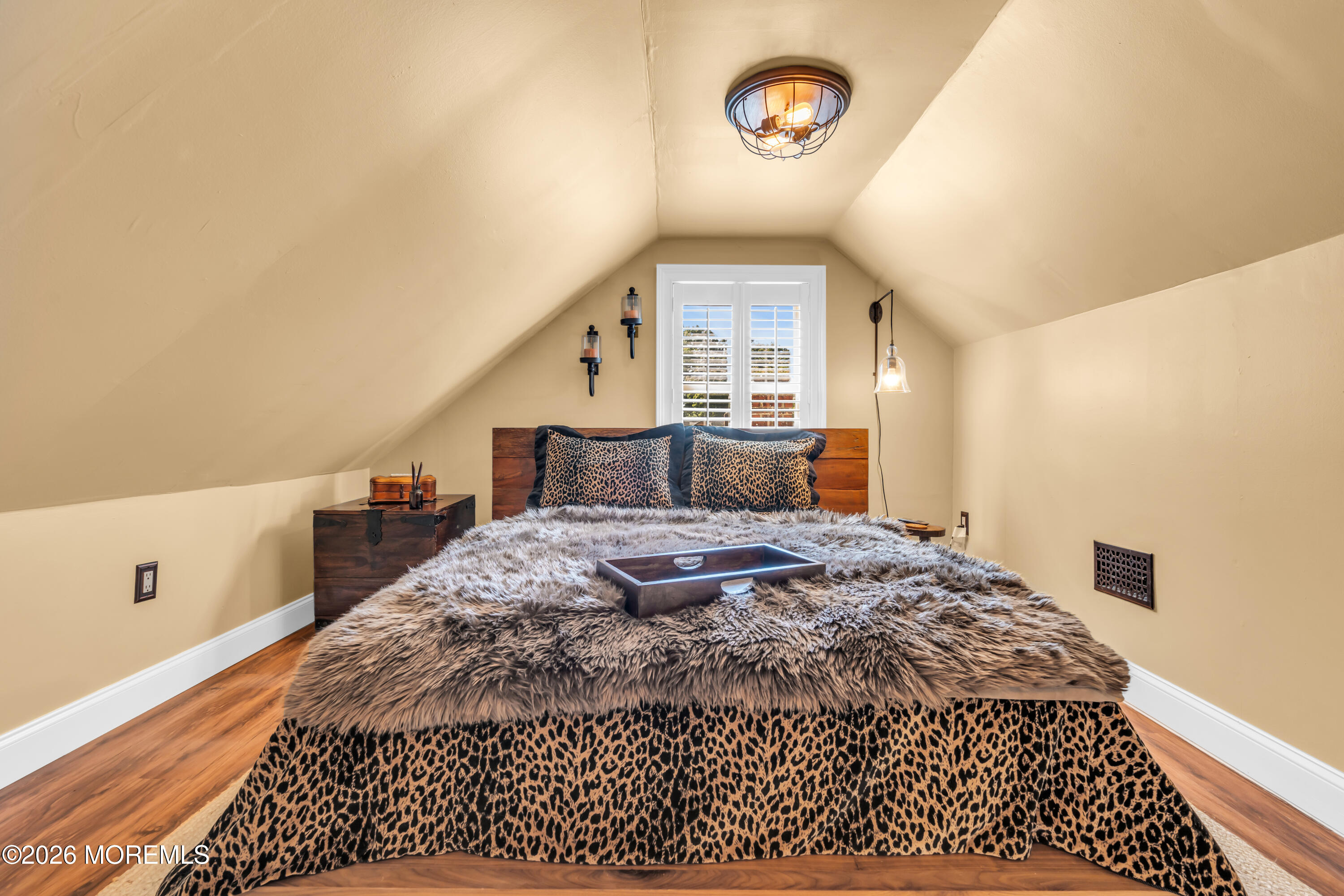 Attic bedroom with a leopard-print bed, gray faux-fur throw, and shuttered window.