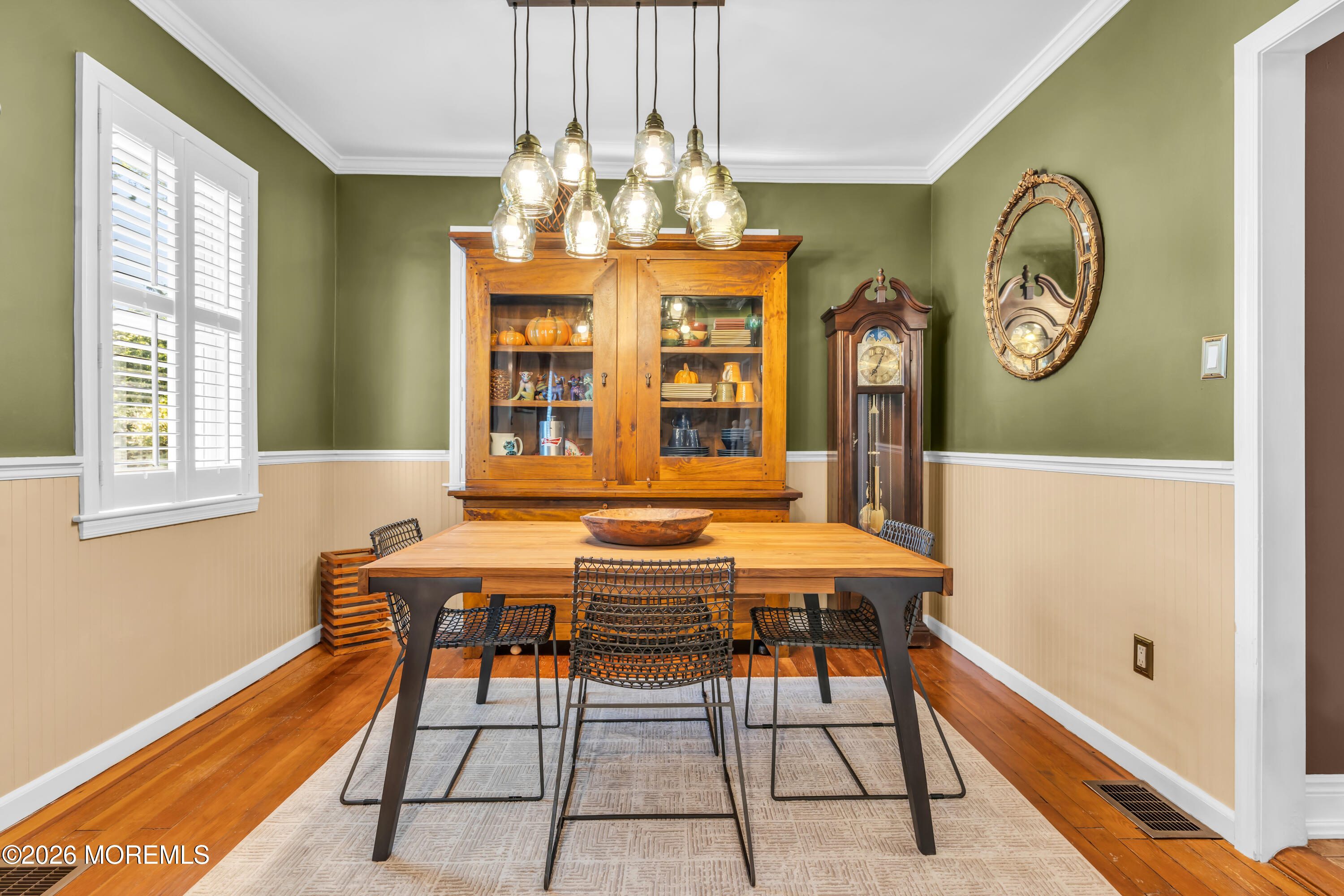 Dining room with a wooden table, glass-front china cabinet, grandfather clock, and hardwood floors.