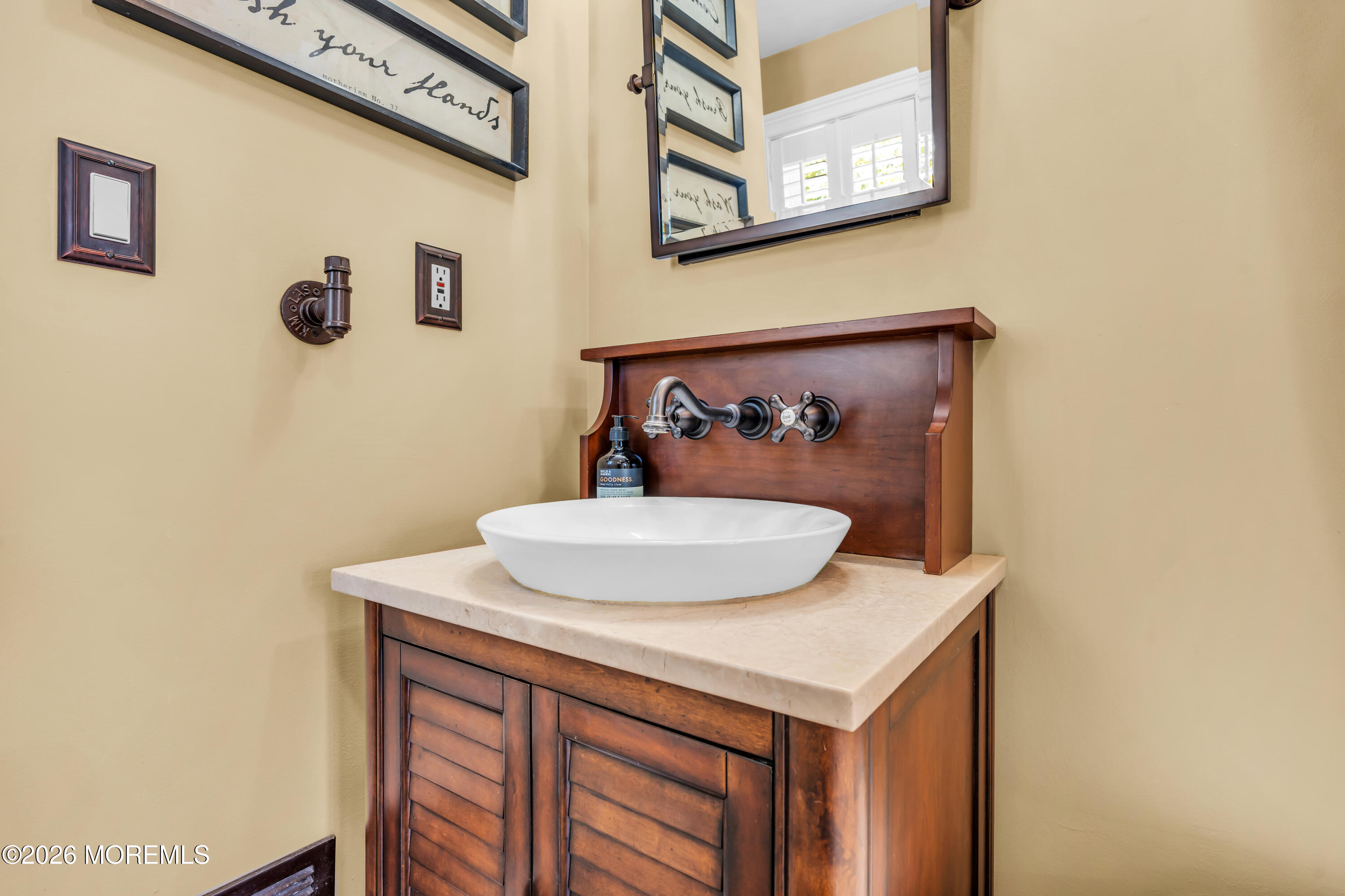 Bathroom vanity with a white vessel sink, dark wood cabinetry, and wall-mounted faucet.