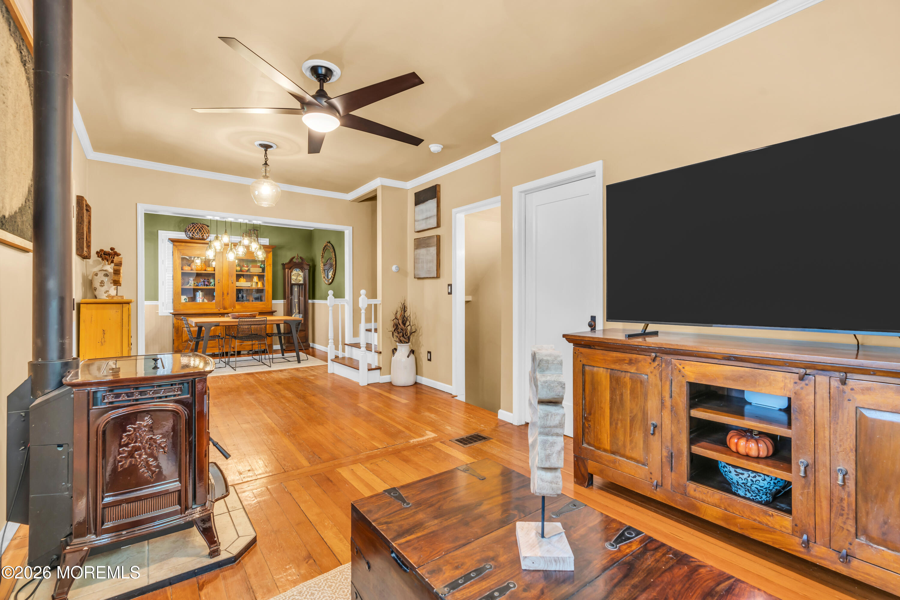 Living room with a freestanding wood stove, hardwood floors, and an adjoining dining area.