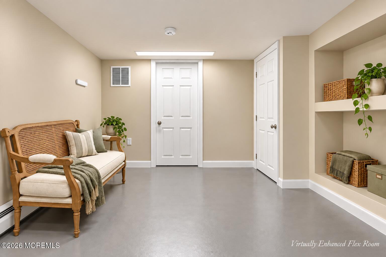 Flex room with a cane-back bench, gray flooring, white doors, and built-in display niches.