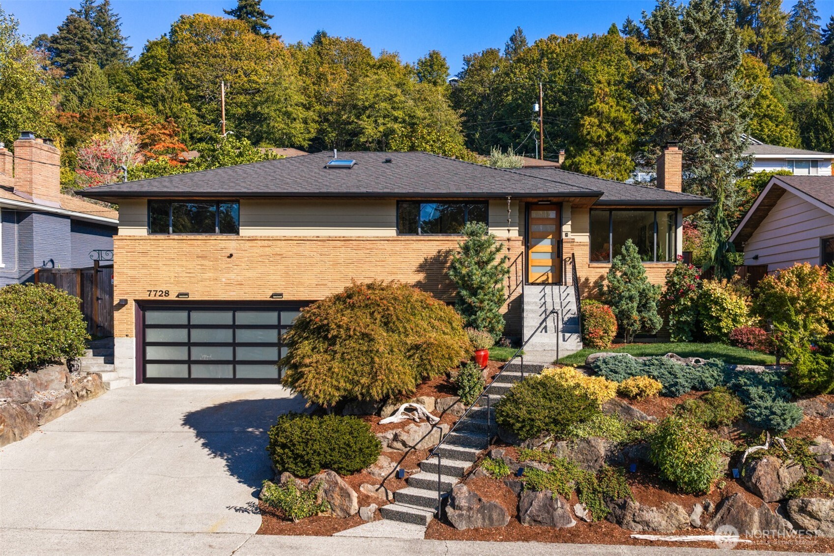 Single-story brick home with an attached garage, landscaped rock garden, and front steps.