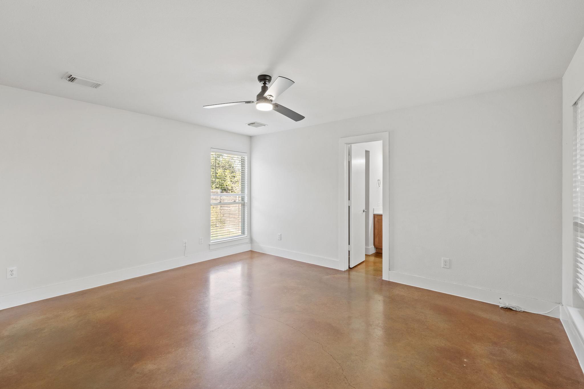 Vacant room with polished concrete flooring, a ceiling fan, and an open doorway.