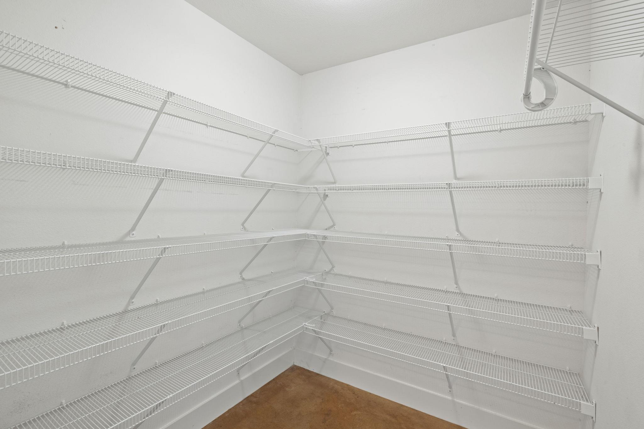 Walk-in closet with white wire shelving along three walls and a brown floor.